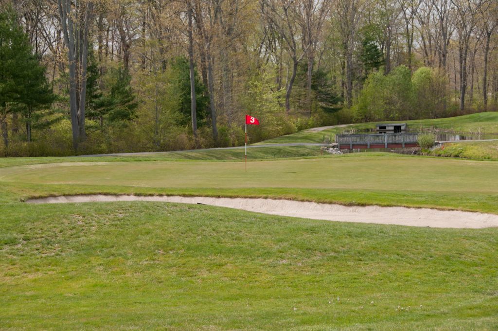 A golf course with a red flag on the green.