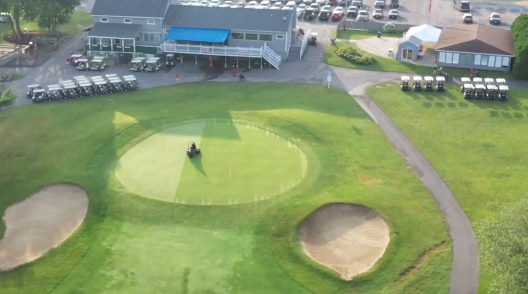 An aerial view of a golf course with houses in the background.