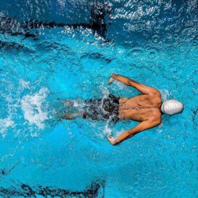 A man is swimming in a swimming pool without a shirt on.