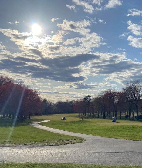 The sun is shining through the clouds over a park