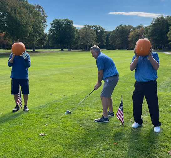 Three men with pumpkins on their heads are playing golf