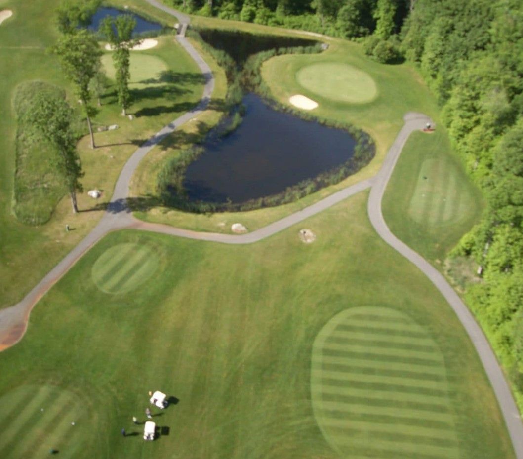 An aerial view of a golf course with a pond in the middle