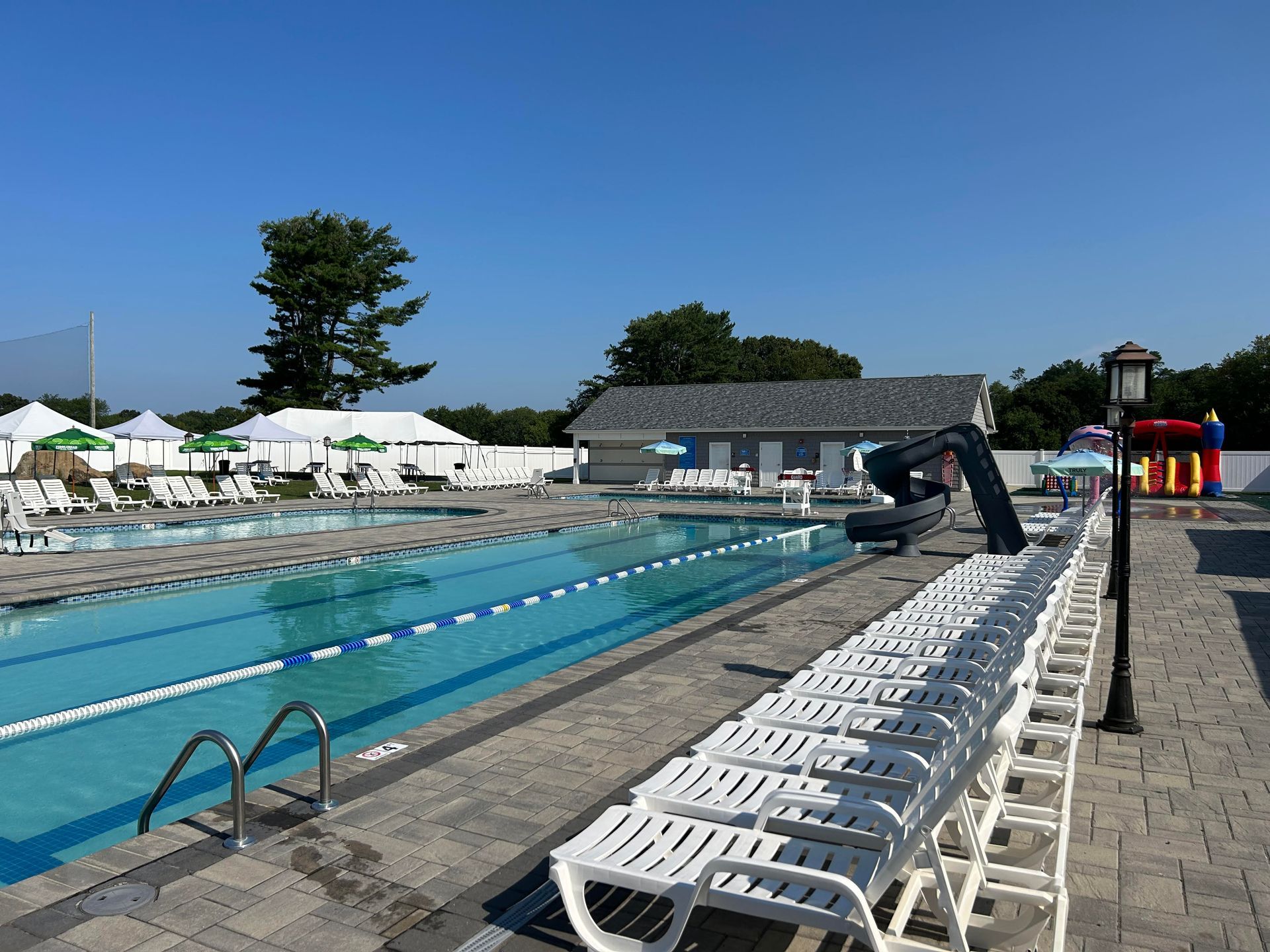 A large swimming pool surrounded by chairs and umbrellas on a sunny day.