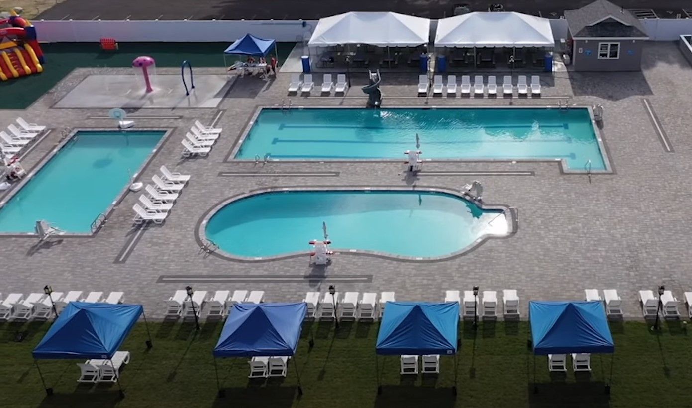 An aerial view of a swimming pool surrounded by blue tents and chairs.