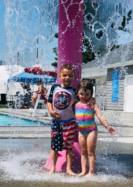 A boy and a girl are standing in front of a water fountain