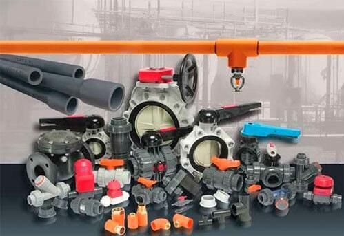 Surtido de tuberías, válvulas y accesorios de PVC en diversas formas y tamaños. Colores naranja y gris.