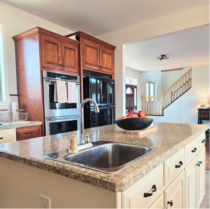 Kitchen island with granite countertop, sink, and wooden cabinets.