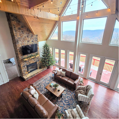 Rustic living room with stone fireplace, leather sofas, and mountain views.