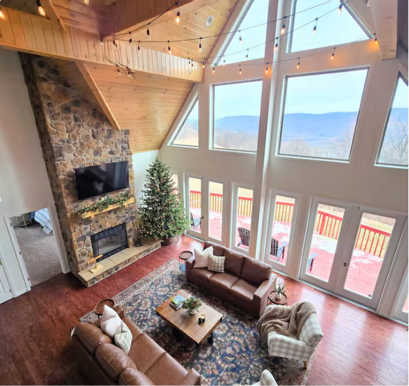 Cozy modern living room with stone fireplace, Christmas tree, and leather sofas.