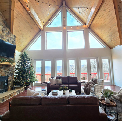 Living room with vaulted ceilings, fireplace, Christmas tree, and seating.