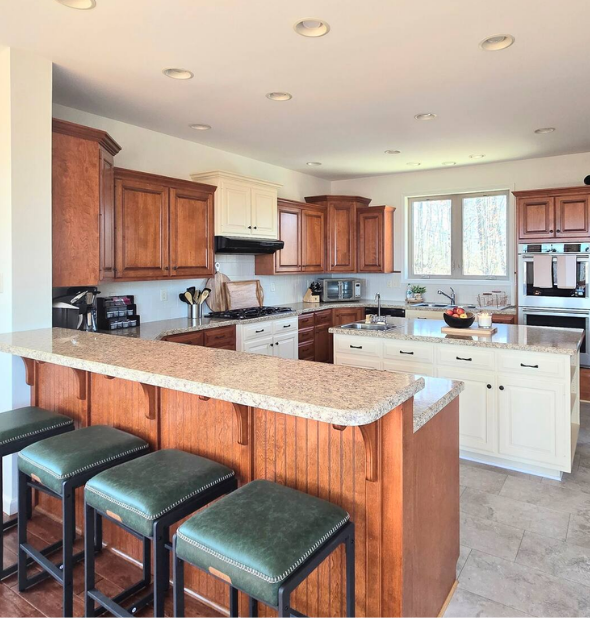 Kitchen with wood island, granite counters, and green stools.