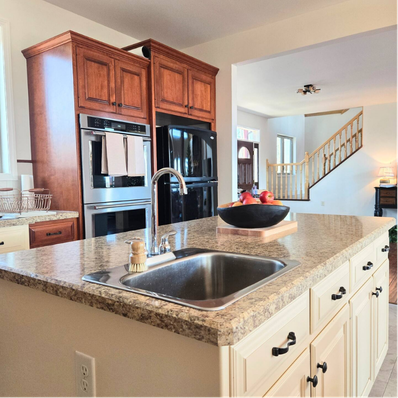 Kitchen island with granite countertop, sink, and wooden cabinets.
