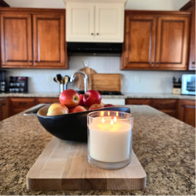 Three-wick candle and apples on kitchen island.
