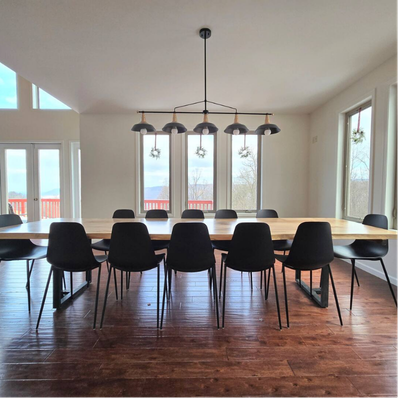 Dining room with light-wood table, black chairs, and pendant lights.