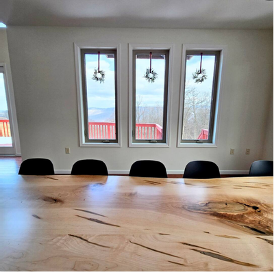 Live-edge wooden dining table with black chairs and window wreaths.