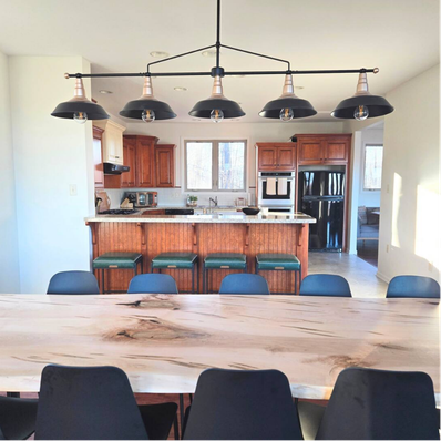 Dining room with live-edge table, black chairs, and wood kitchen.