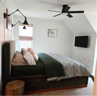 Modern bedroom with green bed, wall lamps, and ceiling fan.