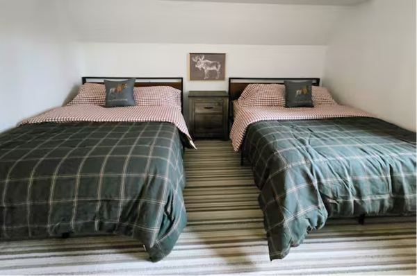 Bedroom with two twin beds, plaid bedding, and nightstand.