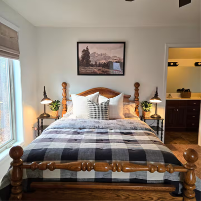 Wooden bed with buffalo plaid bedding and bedside lamps.