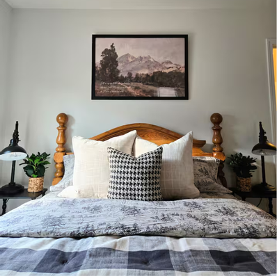 Wooden bed with buffalo check bedding and lamps.