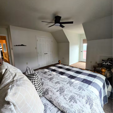Bedroom with bed, black-and-white plaid quilt, and patio door.