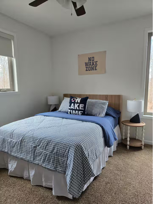 Bedroom with queen bed, blue bedding, and bedside lamps.