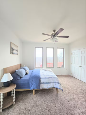 Bedroom with blue bed, wooden headboard, and side table.