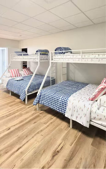 Two white metal bunk beds with blue checkered bedding and pink pillows.