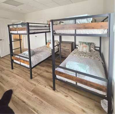 Two bunk beds with metal frames and wood accents in bright room.