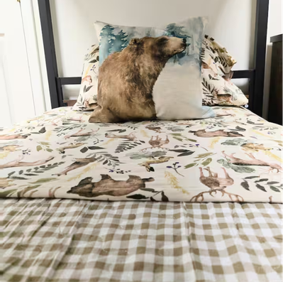 Bed with woodland-themed bedding and bear pillow.