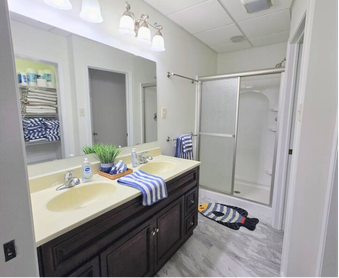 Bathroom with dark wood vanity, double sinks, and walk-in shower.