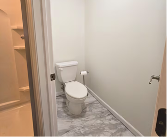 Small bathroom with white toilet and marble-patterned floor.
