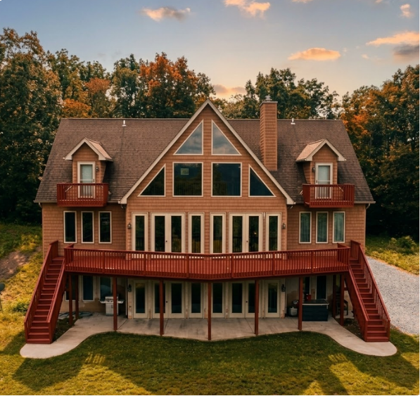Large tan wood cabin with red deck and staircase at sunset.