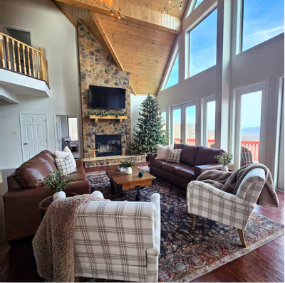 Cozy living room with stone fireplace, sofas, and plaid armchairs.