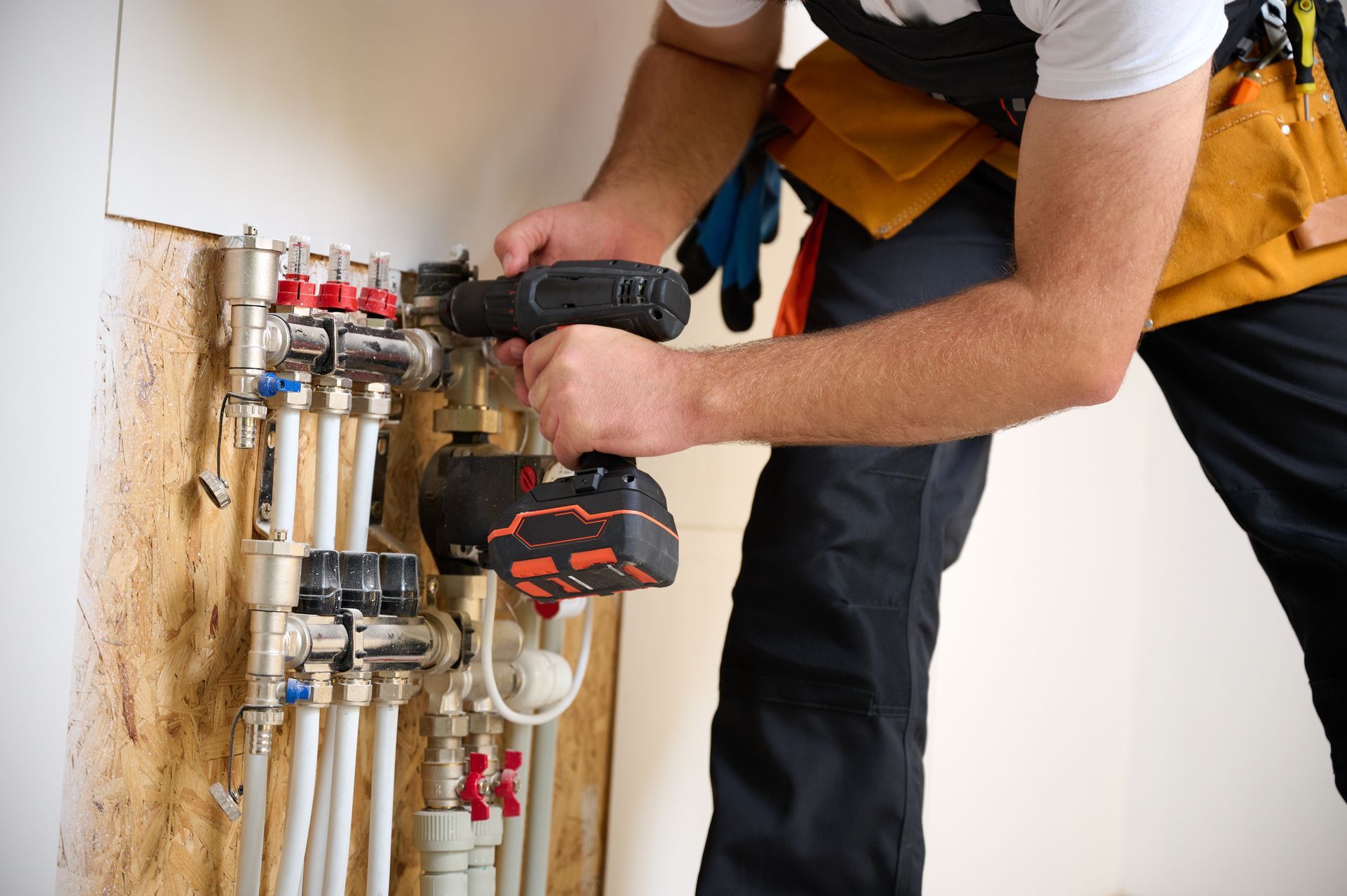 A man is working on a pipe system with a drill.