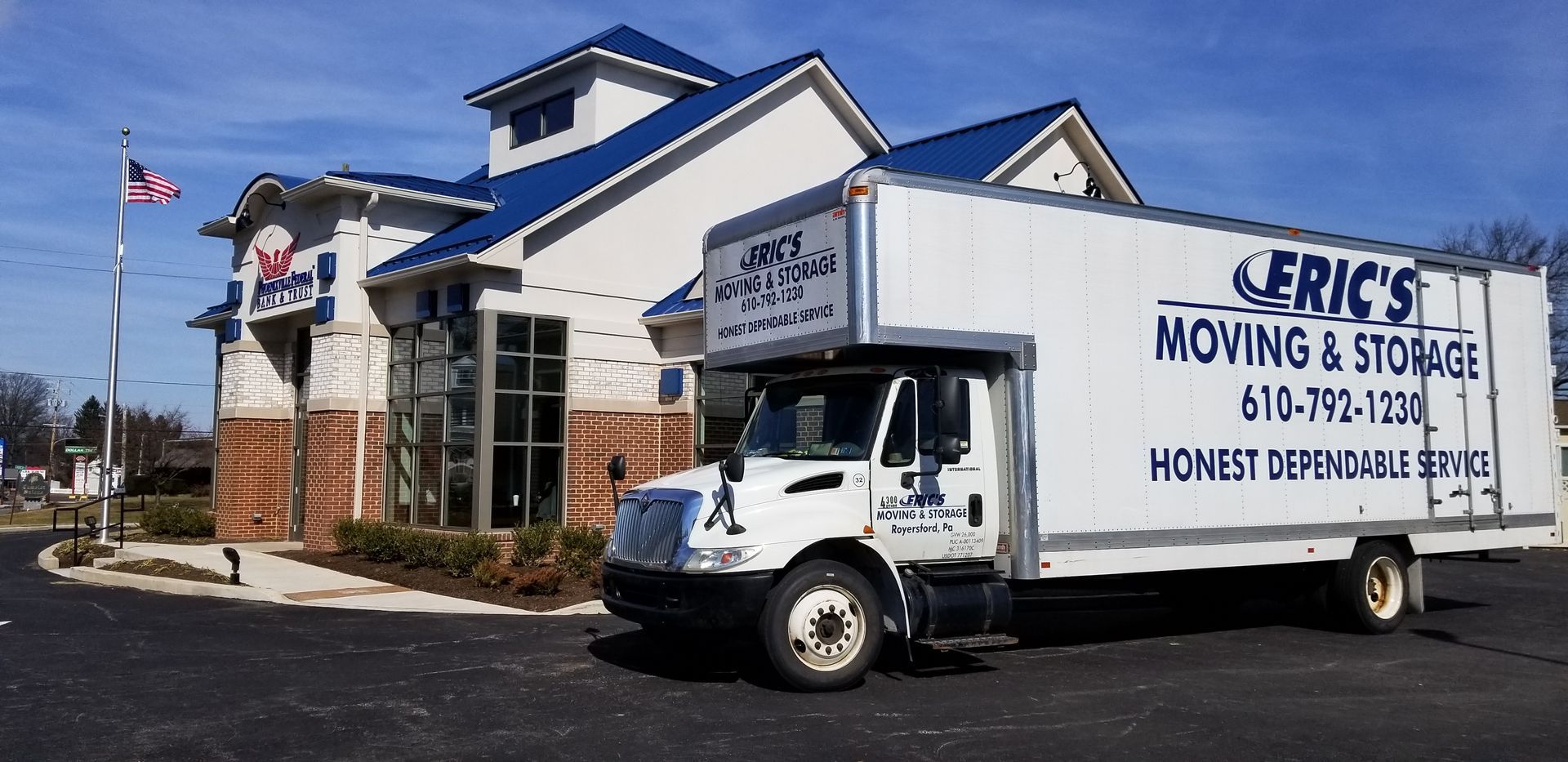 Two movers in blue uniforms carrying cardboard boxes from a van.