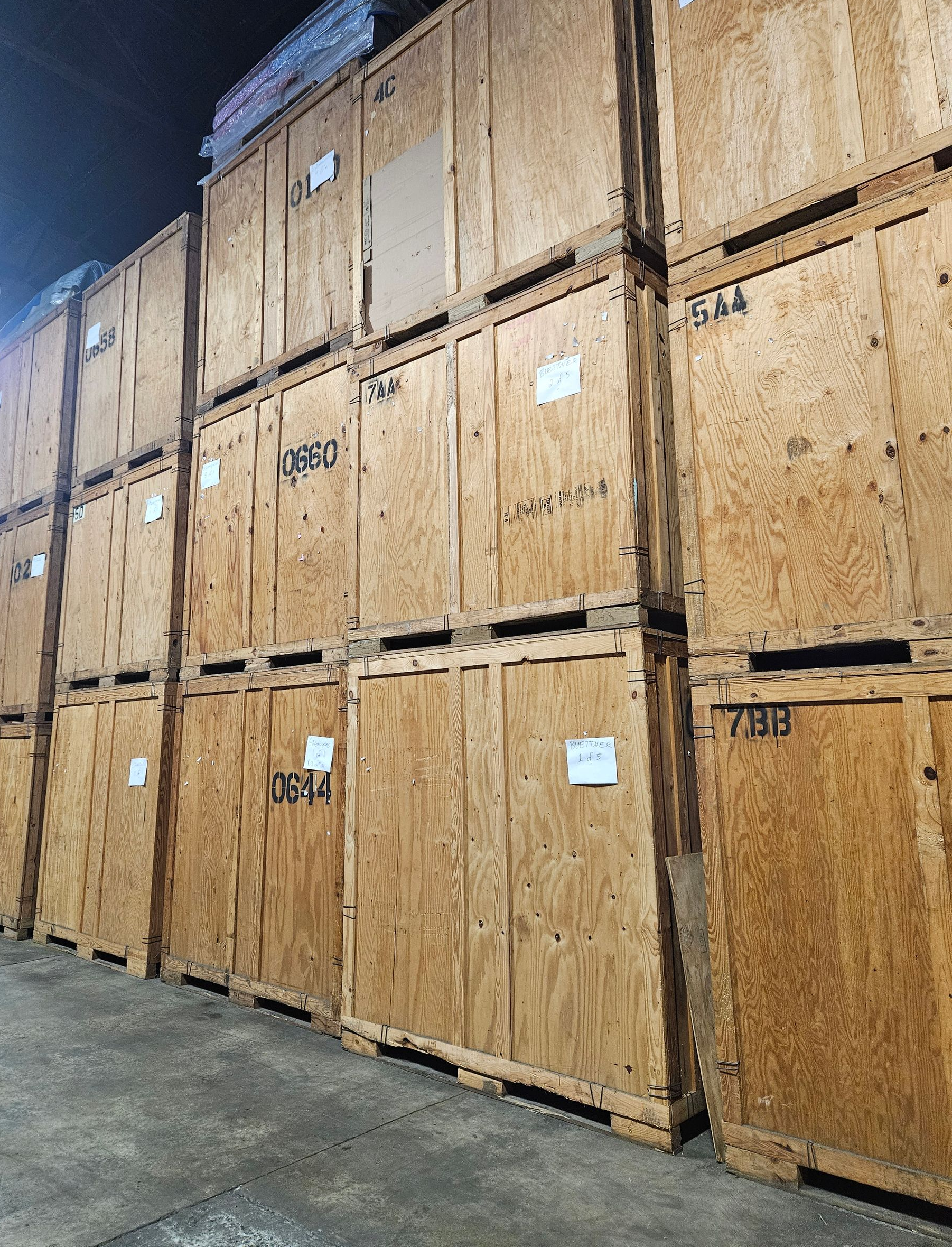 Row of blue storage unit doors with yellow bollards under a blue sky.