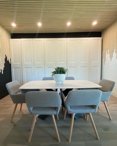 A dining room with a table and chairs and a potted plant on the table.