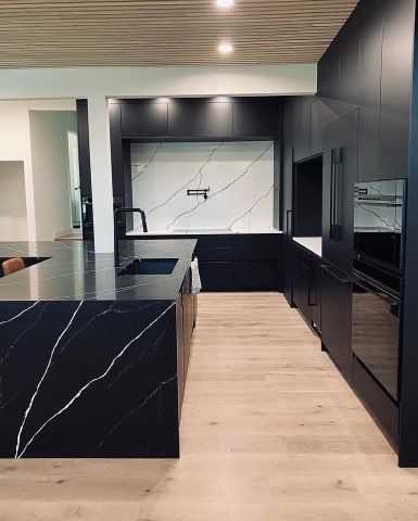 A kitchen with black cabinets and a black granite counter top.