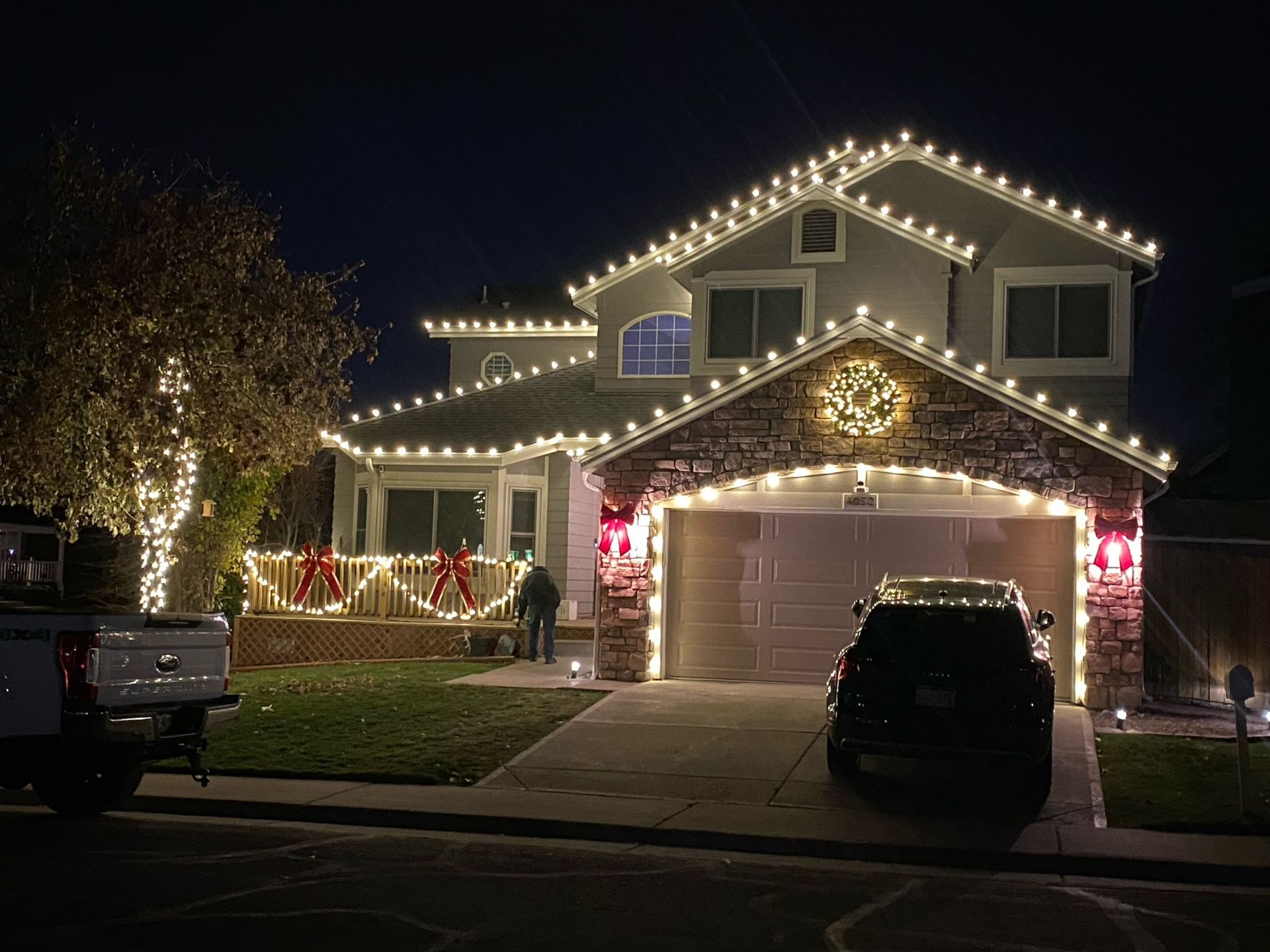 A house is decorated with christmas lights and a car is parked in front of it.