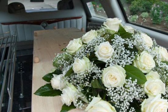 un bouquet di rose bianche su una bara in un carro funebre