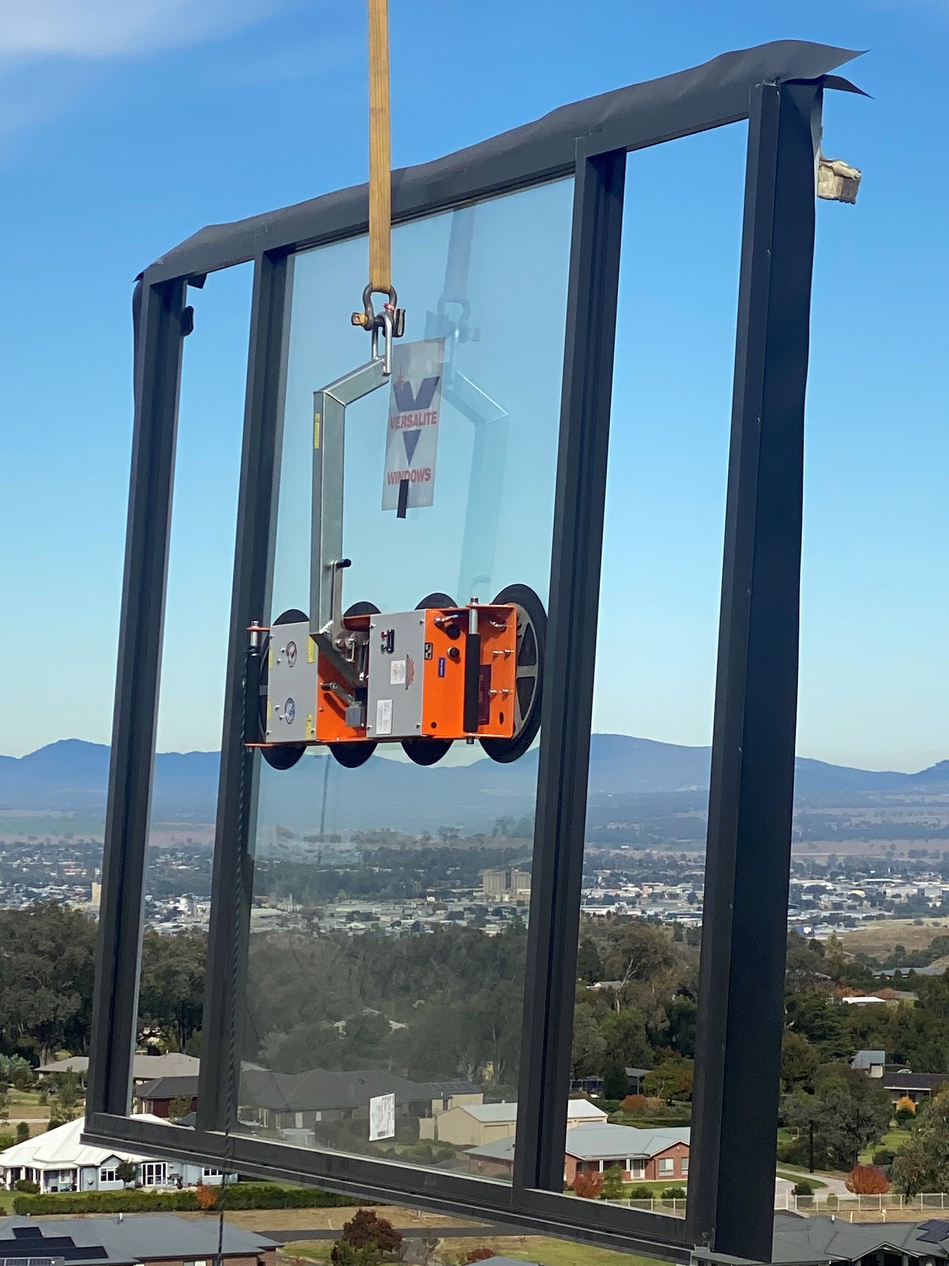 A large piece of glass is being lifted by a crane.
