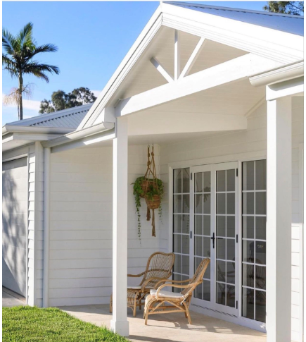 A white house with a porch and chairs on it