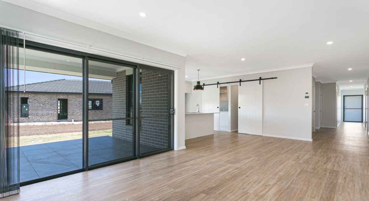 An empty living room with hardwood floors and sliding glass doors.