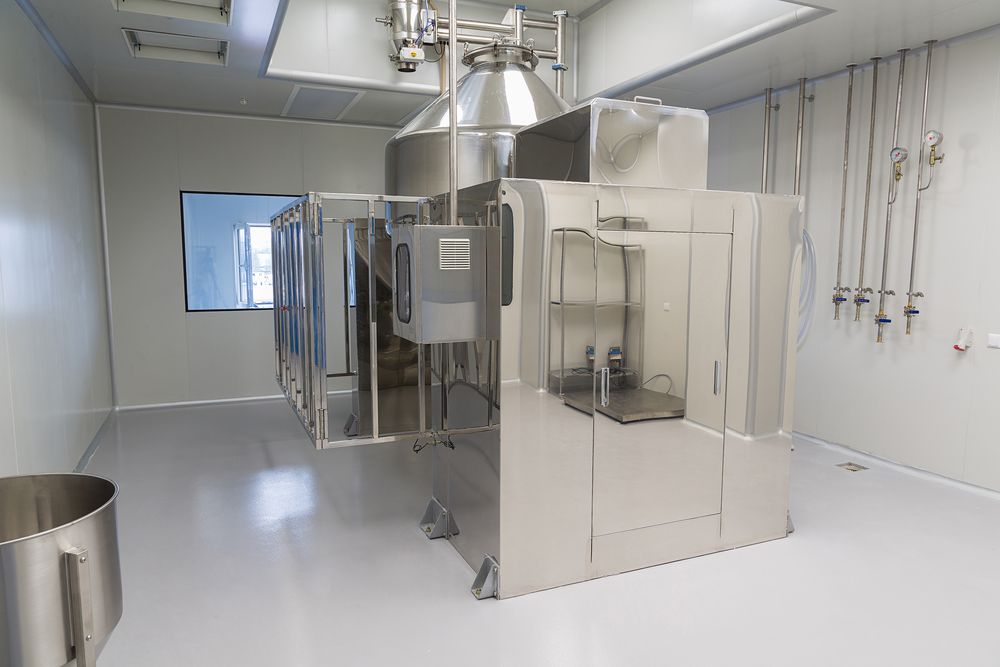 Large industrial stainless steel machine in a clean, clinical laboratory setting with white walls and flooring.
