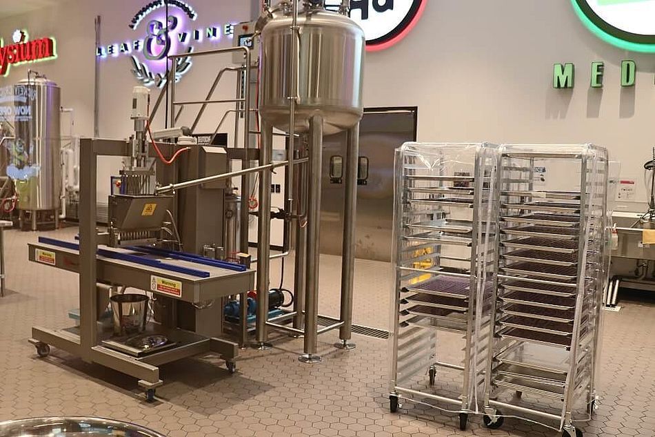 A stainless steel machine is sitting in a kitchen next to a stack of trays.