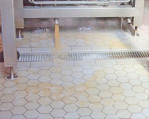 A drain is running down a tiled floor in a kitchen.