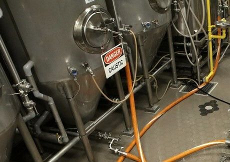 A danger sign is attached to a hose in a brewery.