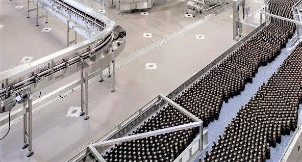 A conveyor belt filled with bottles of beer in a factory.