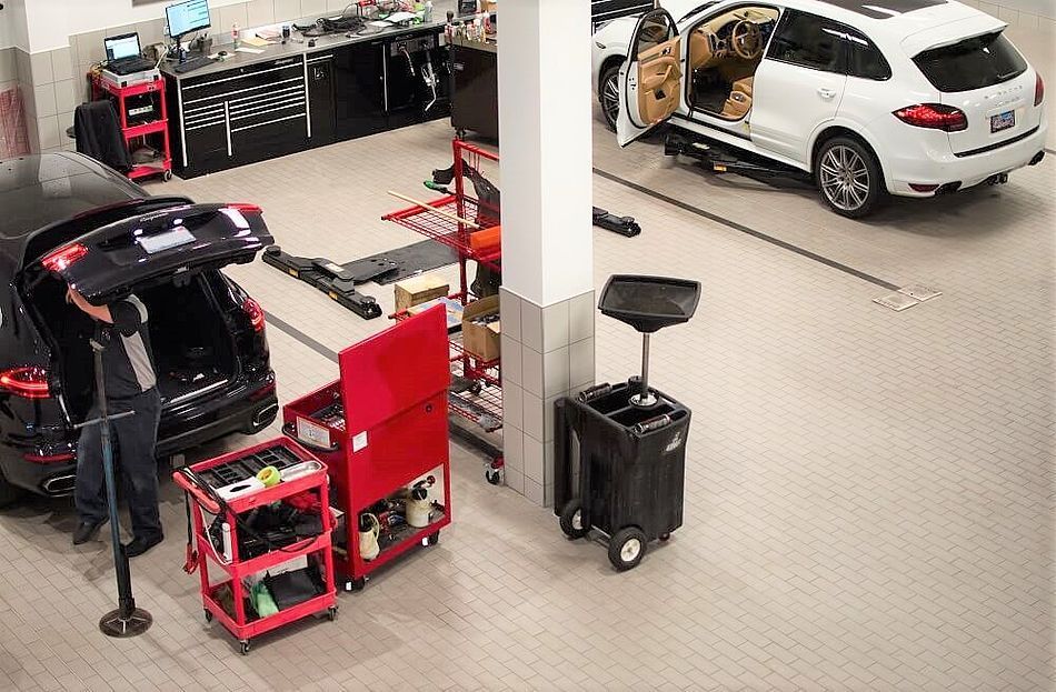 A man is working on a porsche in a garage.